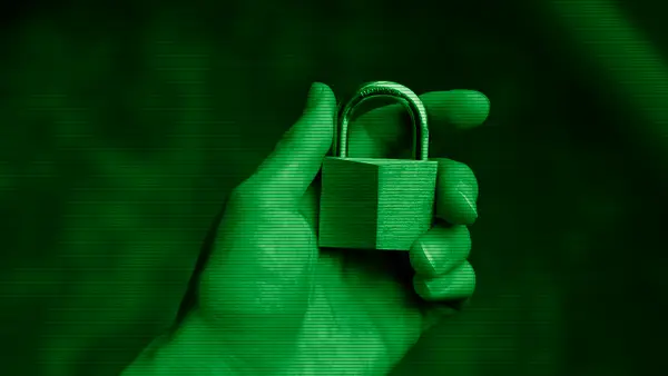 A hand holding a padlock, a symbol of cybersecurity